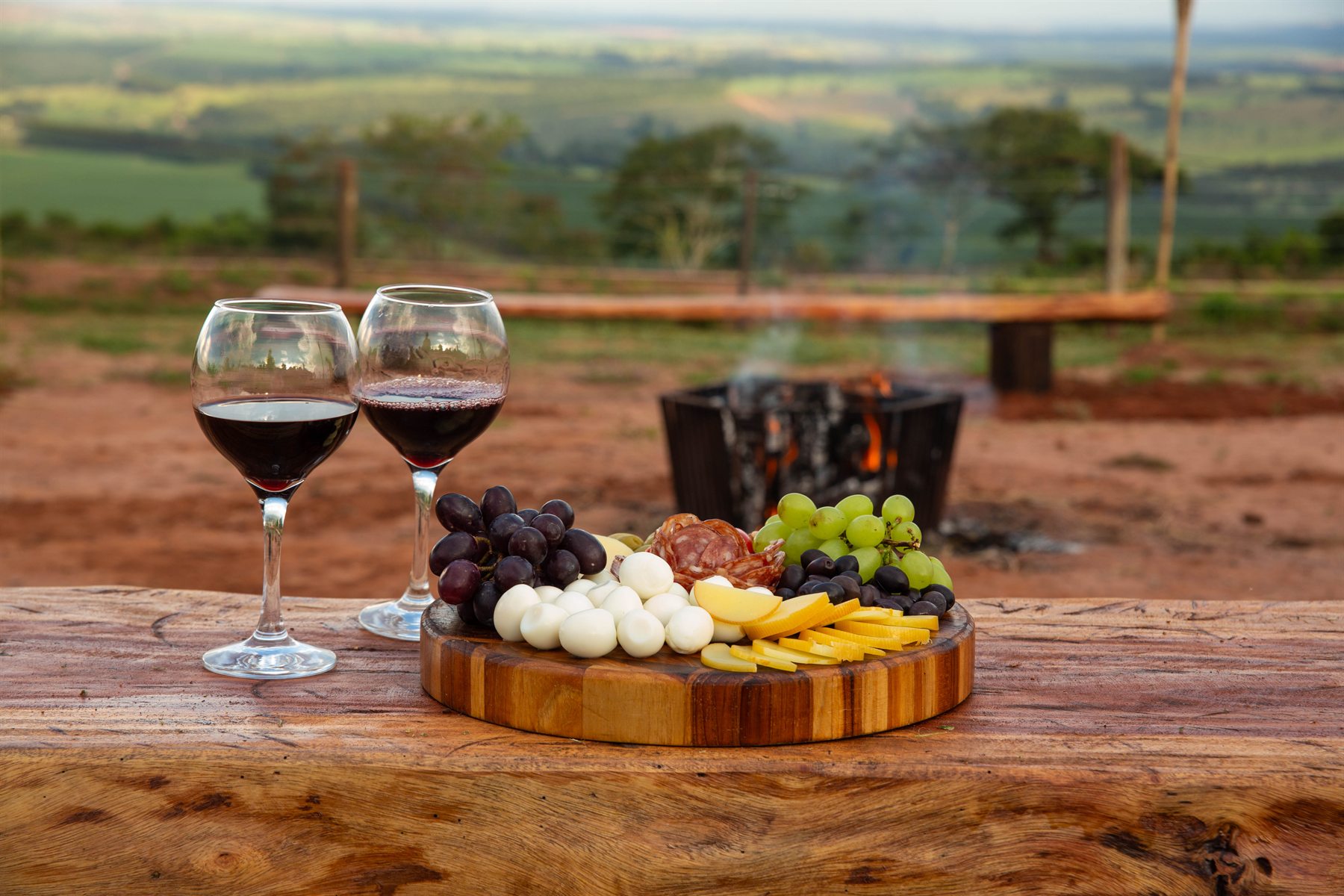 Taças de vinho e tábua de frios diante da fogueira, no alto do mirante